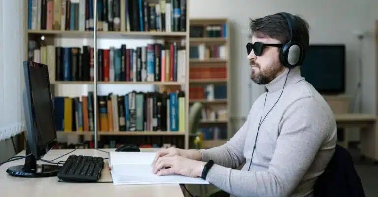 Blog 108 Blind man using a screen reader and braille display alongside his computer to navigate a website, illustrating ADA website compliance and accessibility for people with disabilities