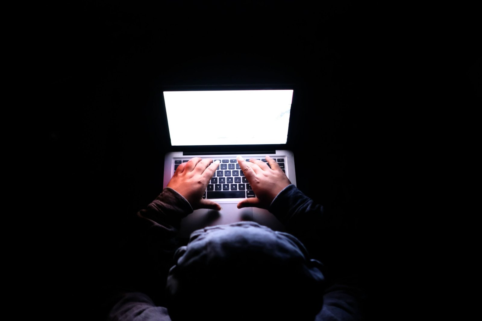 Laptop glowing in a dark room representing website content being crawled under new Meta business terms